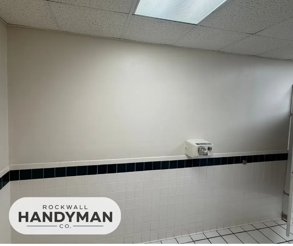 Bathroom interior with freshly painted white walls above tiled wainscoting.