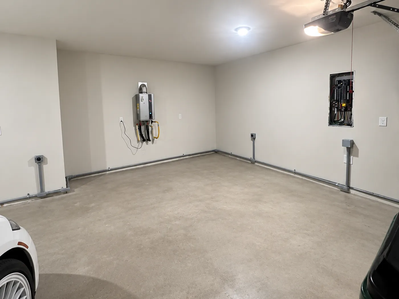 Garage interior with three surface-mounted 240-volt outlet boxes on conduit stubs along the walls, the runs returning to an electrical panel.